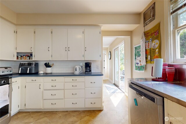 kitchen featuring dishwasher, dark countertops, backsplash, and a healthy amount of sunlight