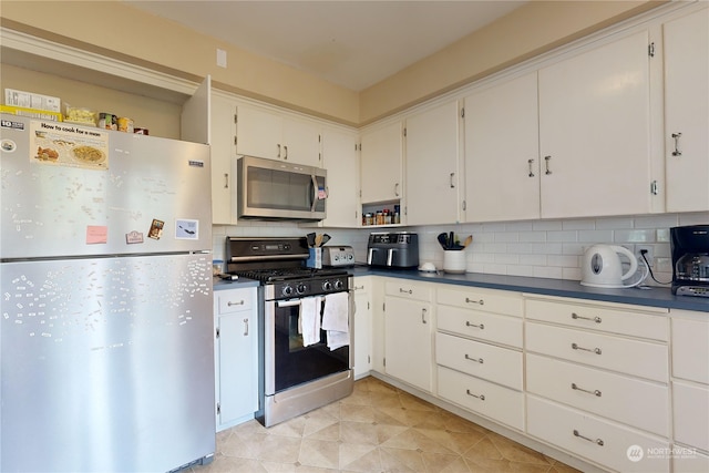 kitchen featuring appliances with stainless steel finishes, dark countertops, white cabinets, and tasteful backsplash