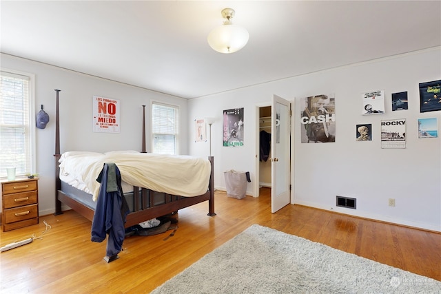 bedroom featuring baseboards, multiple windows, and light wood finished floors