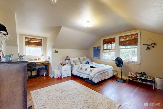 bedroom featuring lofted ceiling, multiple windows, and wood finished floors