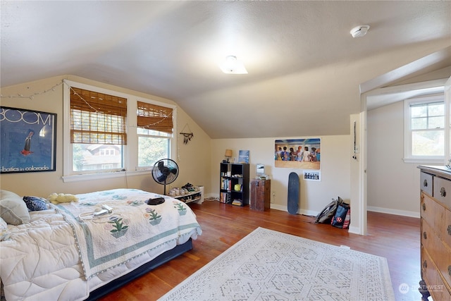 bedroom featuring lofted ceiling, multiple windows, and wood finished floors