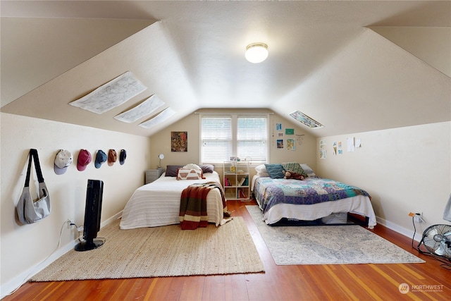 bedroom featuring lofted ceiling, wood finished floors, and baseboards