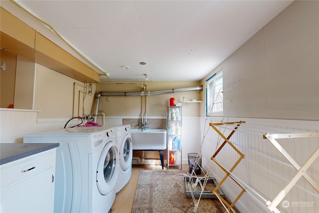 laundry area featuring laundry area, a wainscoted wall, a sink, and washer and clothes dryer