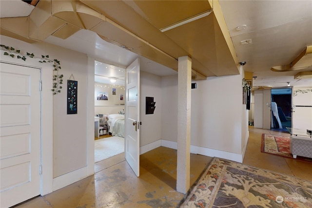 corridor featuring concrete floors and baseboards