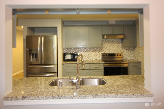 kitchen with sink, appliances with stainless steel finishes, light stone countertops, and backsplash