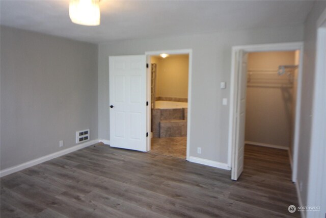 unfurnished bedroom featuring a spacious closet, dark hardwood / wood-style floors, and a closet