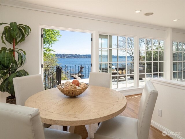 dining area featuring a water view, crown molding, and hardwood / wood-style floors