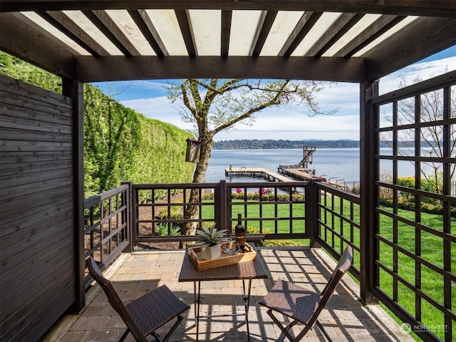 wooden deck with a water view, a lawn, and a pergola