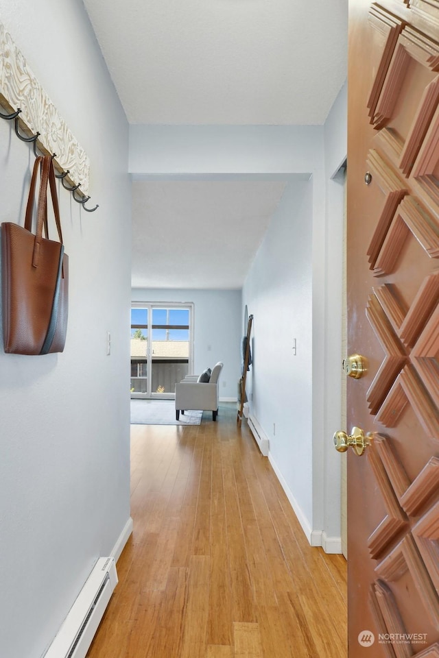 corridor with light hardwood / wood-style floors and a baseboard heating unit