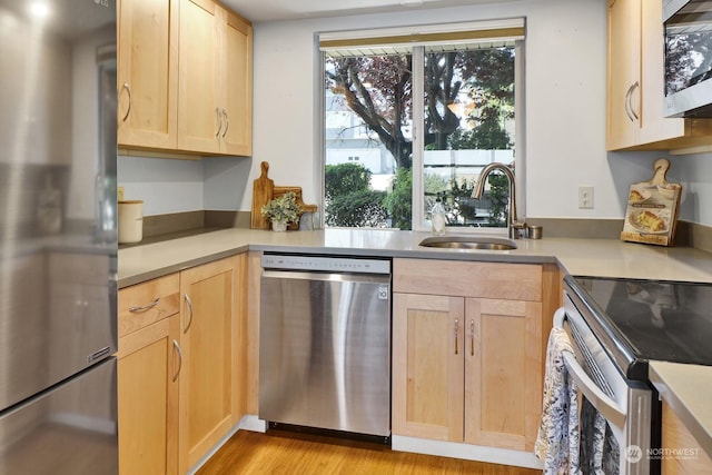 kitchen featuring light wood-type flooring, appliances with stainless steel finishes, sink, and light brown cabinets