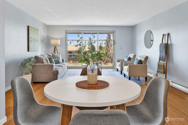 dining area with hardwood / wood-style floors, a textured ceiling, and baseboard heating