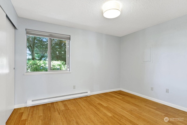 unfurnished room featuring hardwood / wood-style floors, a textured ceiling, and baseboard heating