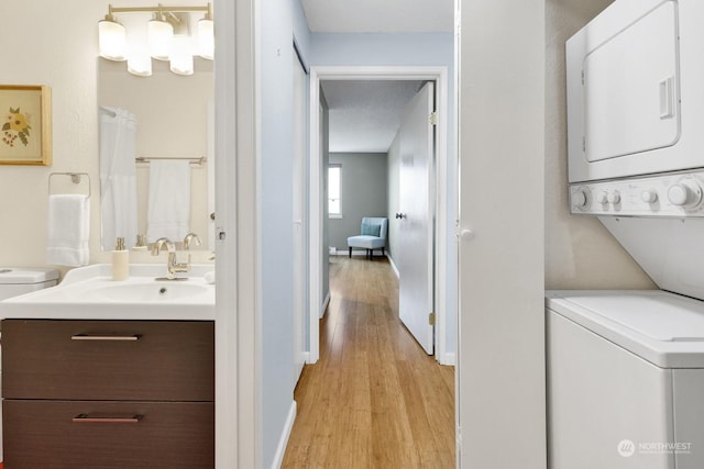 interior space featuring stacked washer / drying machine, sink, light hardwood / wood-style flooring, and a textured ceiling