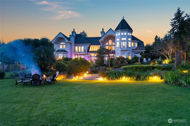 back house at dusk with a lawn and a fire pit