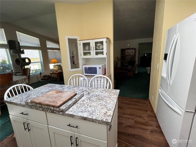 kitchen with white cabinetry, white appliances, and light stone counters