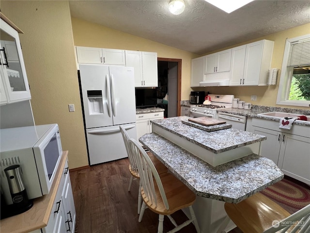 kitchen with a kitchen breakfast bar, vaulted ceiling, white cabinets, and white appliances