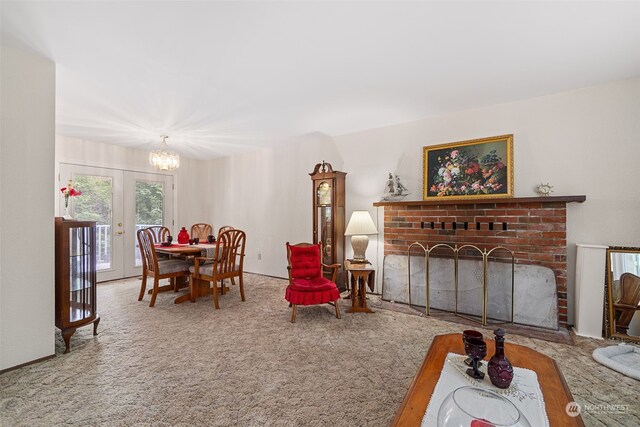 living room with french doors, a brick fireplace, a notable chandelier, and carpet