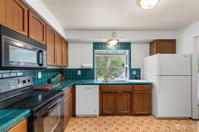 kitchen with tile countertops, sink, decorative backsplash, black appliances, and a textured ceiling