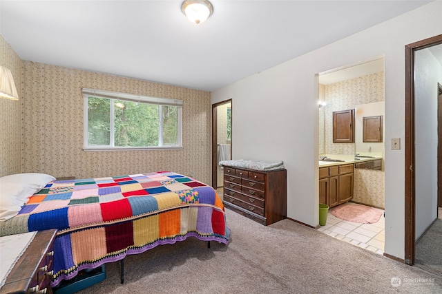 carpeted bedroom featuring connected bathroom and sink