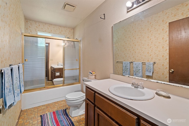 full bathroom with vanity, a textured ceiling, shower / bath combination with glass door, and toilet