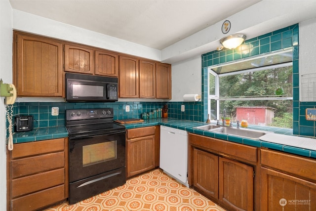 kitchen featuring tasteful backsplash, sink, tile counters, light tile patterned floors, and black appliances