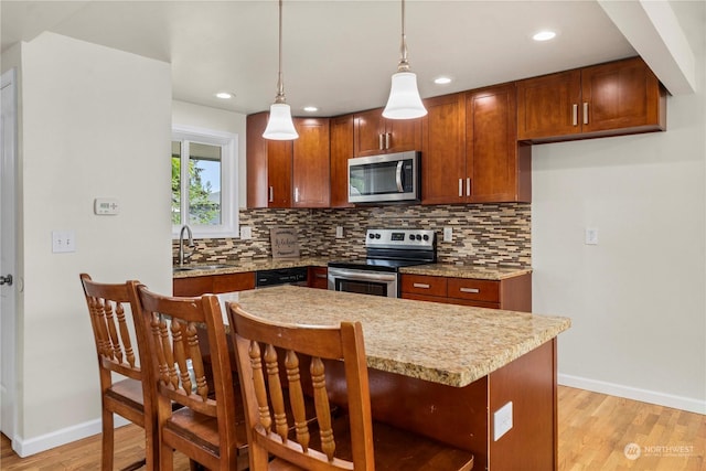 kitchen featuring appliances with stainless steel finishes, tasteful backsplash, sink, hanging light fixtures, and light hardwood / wood-style floors