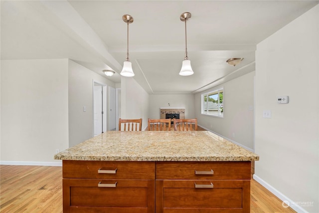 kitchen with hanging light fixtures, light hardwood / wood-style flooring, and light stone countertops