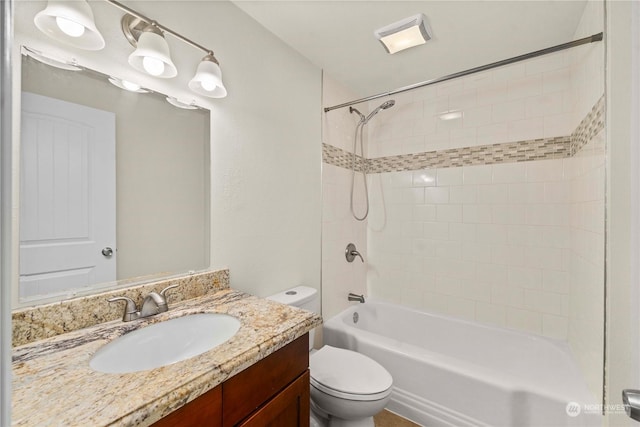 full bathroom featuring vanity, tiled shower / bath, and toilet