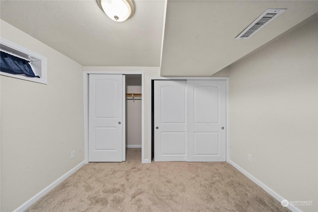 unfurnished bedroom featuring light carpet and a textured ceiling