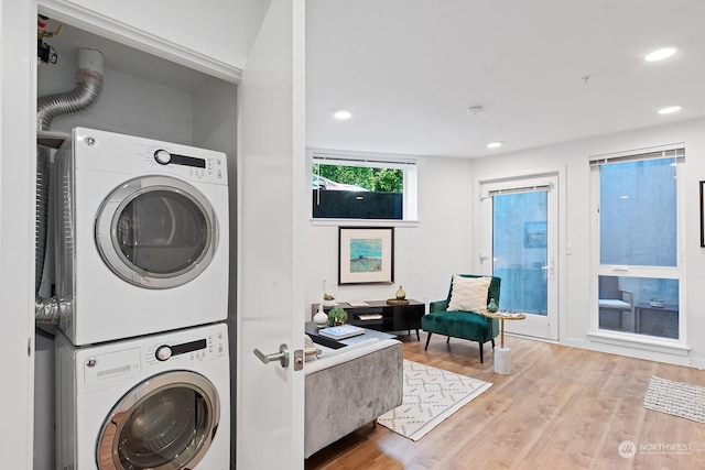 washroom with stacked washer / drying machine and light hardwood / wood-style flooring