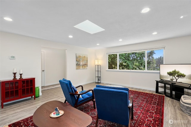 living room featuring wood-type flooring and a skylight