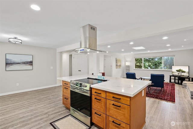 kitchen featuring a kitchen island, stainless steel range with electric cooktop, island exhaust hood, light stone counters, and light hardwood / wood-style flooring