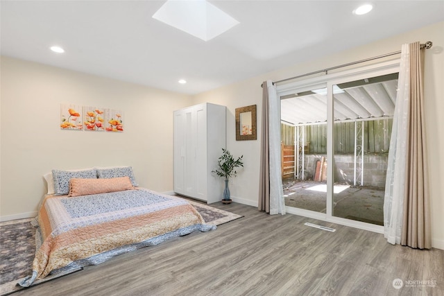 bedroom with a skylight, light hardwood / wood-style flooring, and access to outside