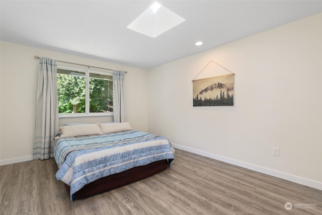 bedroom featuring hardwood / wood-style floors and a skylight