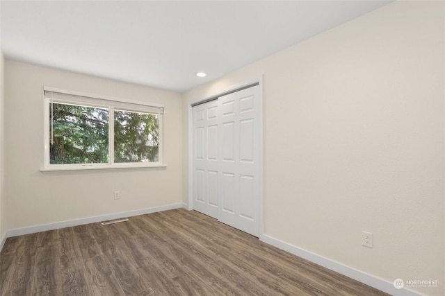 unfurnished bedroom with dark hardwood / wood-style floors and a closet