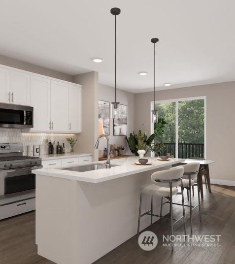 kitchen featuring decorative light fixtures, an island with sink, white cabinets, and stainless steel appliances