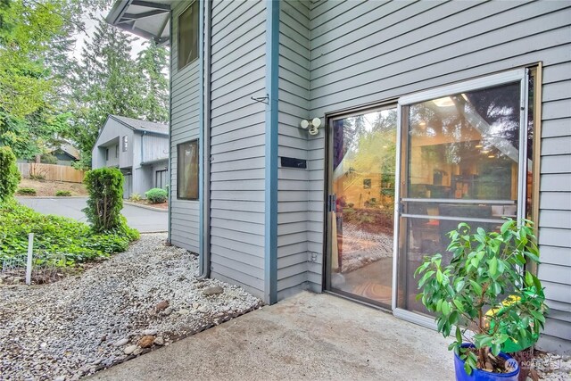 view of exterior entry featuring a patio area and fence