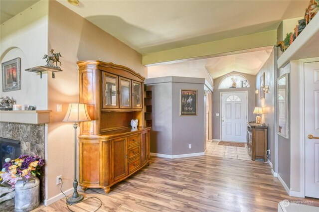 entrance foyer featuring lofted ceiling, a tiled fireplace, and light wood-type flooring