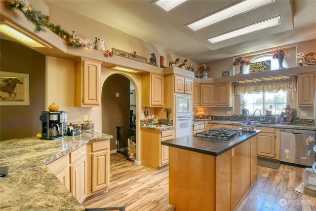 kitchen with sink, a center island, light wood-type flooring, light brown cabinets, and stainless steel appliances