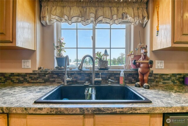 kitchen with dishwashing machine, light stone countertops, and sink