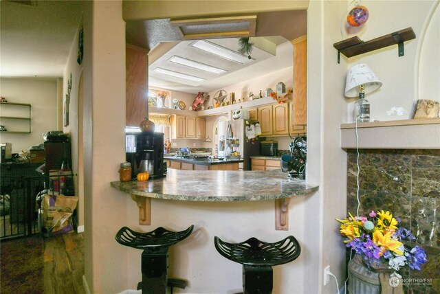 kitchen with kitchen peninsula, light brown cabinetry, and stainless steel fridge with ice dispenser