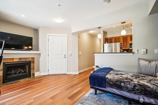 bedroom featuring a fireplace, stainless steel refrigerator, and light wood-type flooring