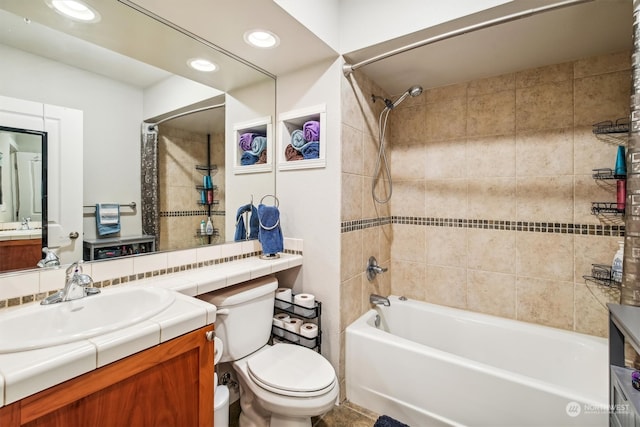 full bathroom featuring vanity, tiled shower / bath, and toilet