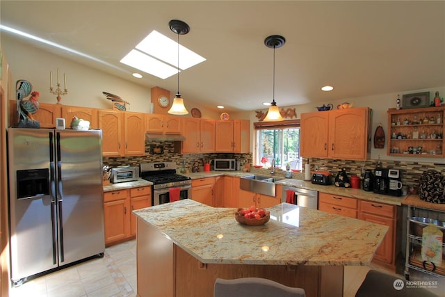 kitchen featuring pendant lighting, stainless steel appliances, a sink, a kitchen island, and under cabinet range hood