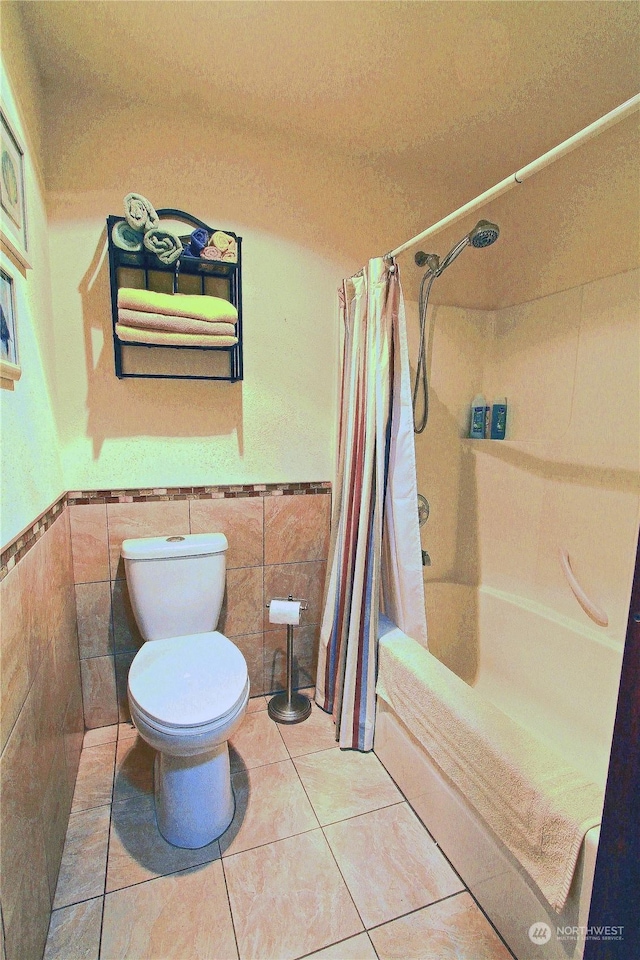 bathroom with a wainscoted wall, tile patterned flooring, tile walls, and shower / tub combo with curtain