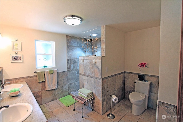 full bathroom with toilet, double vanity, tile walls, and a sink