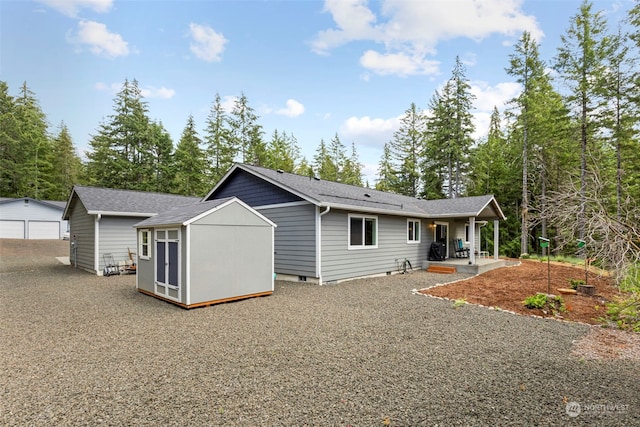 rear view of house with a shingled roof, crawl space, and a patio area