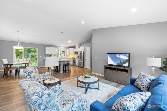 living room featuring light wood-style floors, vaulted ceiling, and baseboards