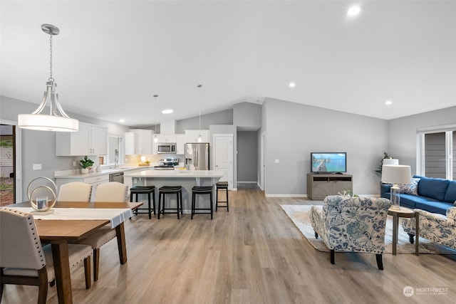 living area featuring light wood finished floors, baseboards, vaulted ceiling, and recessed lighting