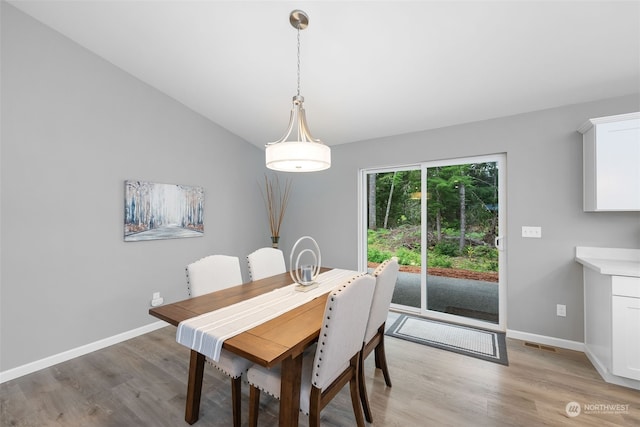 dining space featuring lofted ceiling, light wood finished floors, and baseboards